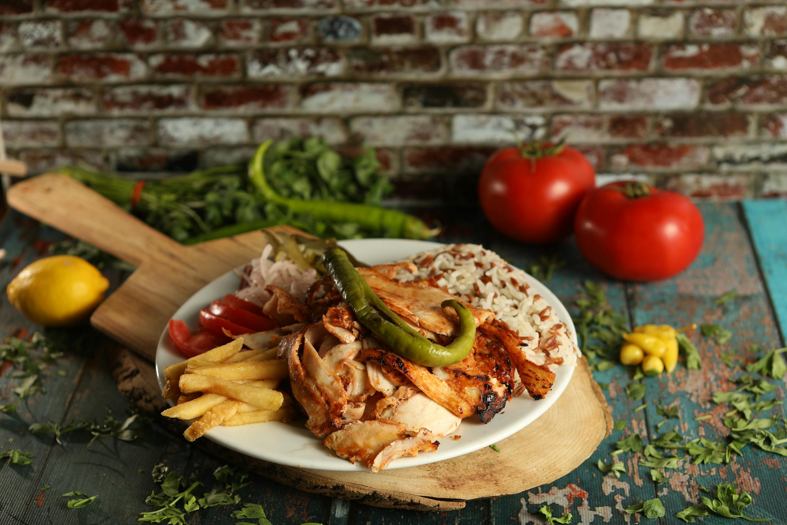 A mouthwatering plate of Turkish doner kebab with fries, rice, and vegetables in a rustic setting.