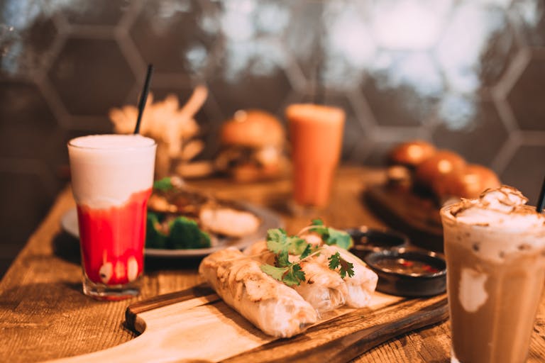 Close-up of a delicious meal with colorful cocktails on a wooden table, perfect for food enthusiasts.