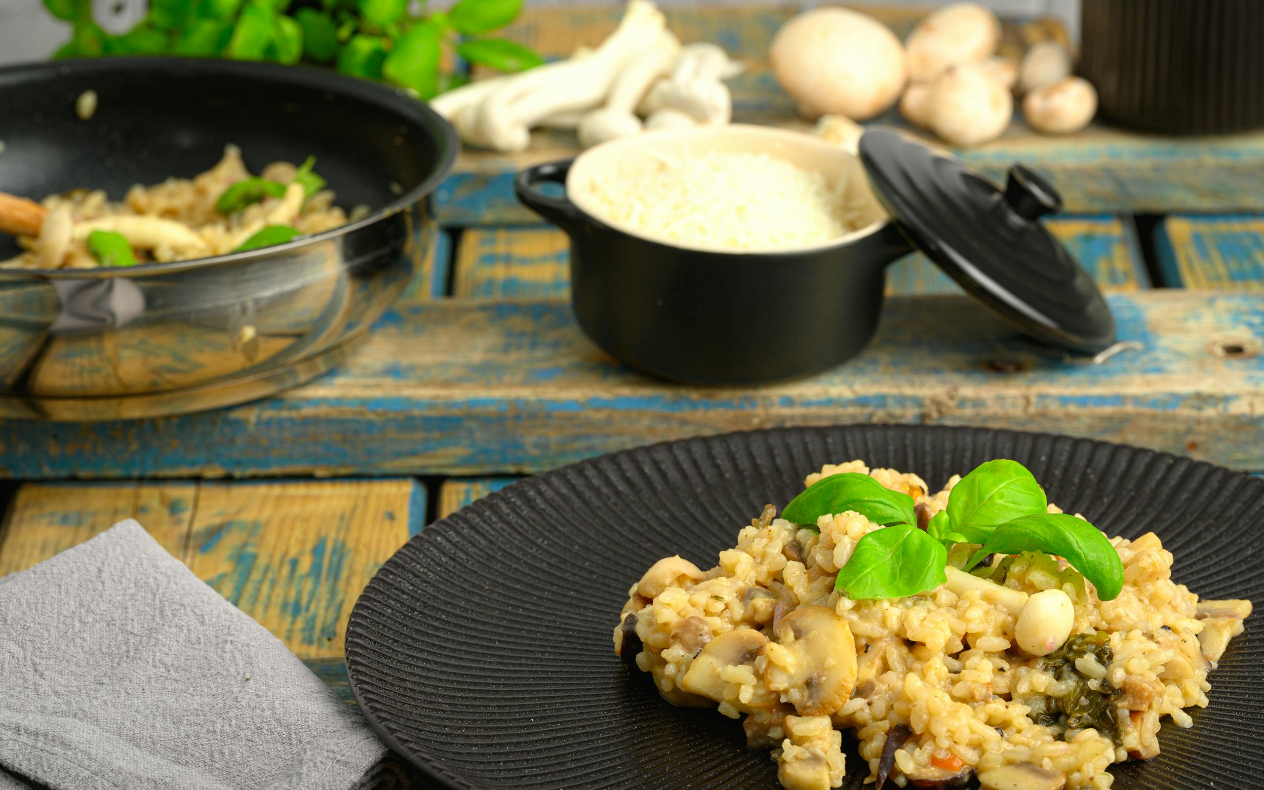 Close-up of creamy mushroom risotto with rice and basil, styled on a rustic wooden table.