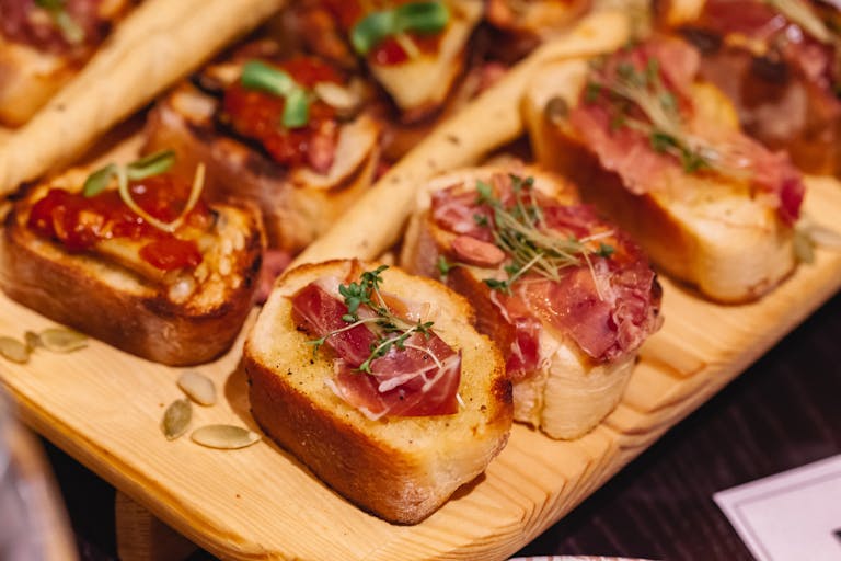 Delicious bruschetta with prosciutto and herbs served on a rustic wooden board. Perfect for appetizers.