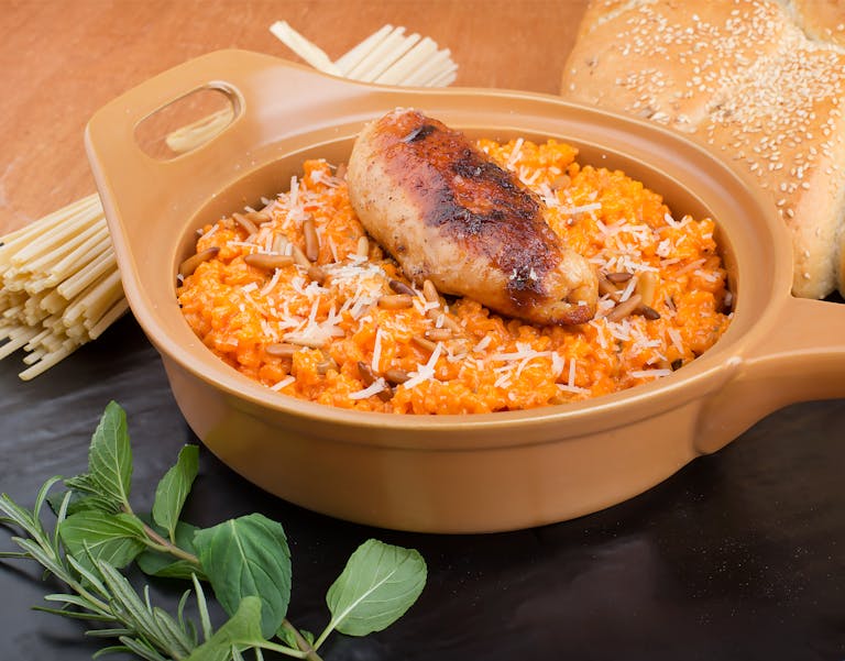 Delicious chicken risotto with herbs and bread on a table.