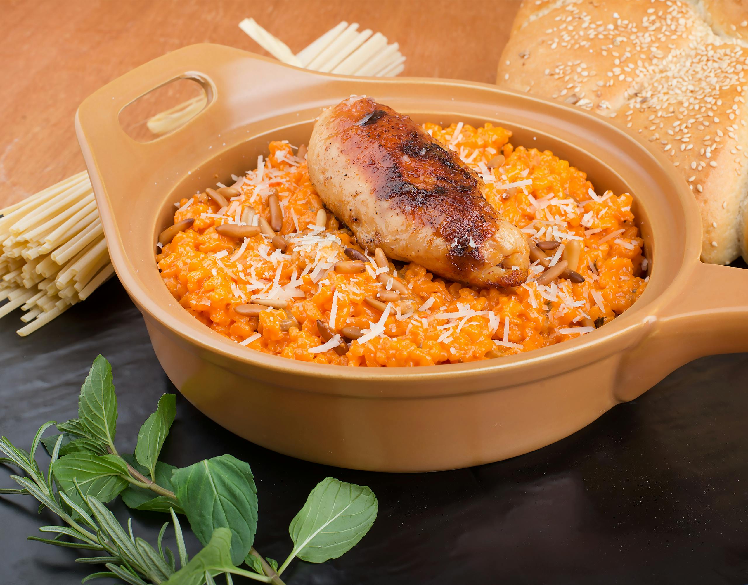 Delicious chicken risotto with herbs and bread on a table.