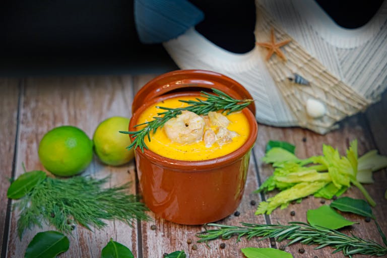Delicious seafood soup with shrimp, rosemary, and lime garnish in a rustic setting.