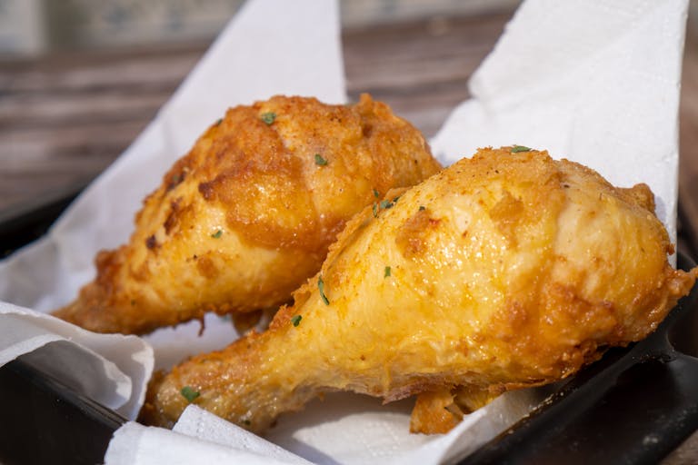 Two crispy fried chicken drumsticks on a plate, showcasing golden brown texture.