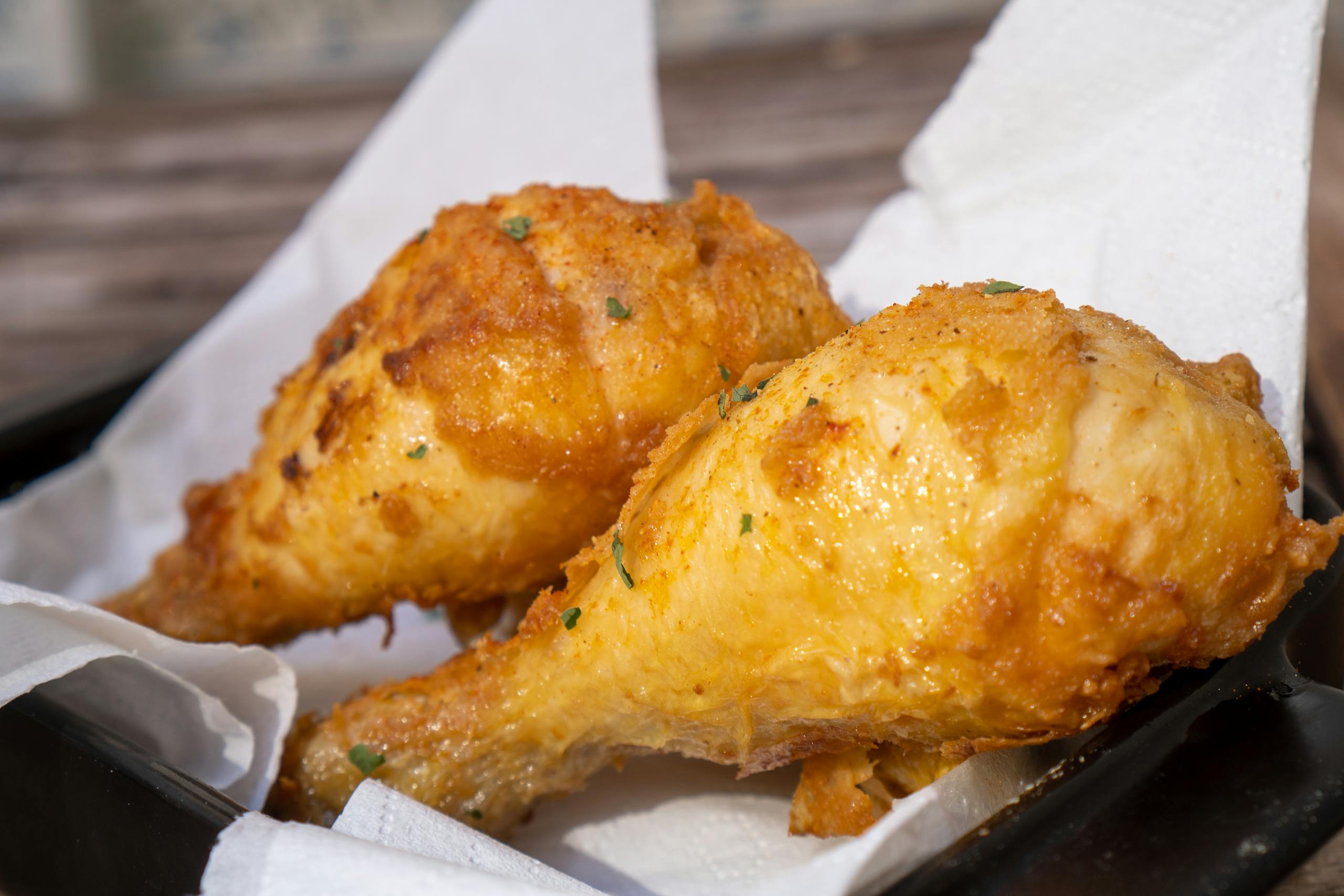 Two crispy fried chicken drumsticks on a plate, showcasing golden brown texture.